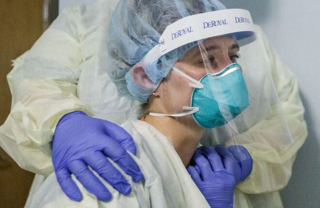 Tallahassee Memorial HealthCare nurse Charlee Mehr sits on the bed next to her patient to comfort him as he dies of COVID-19 on August 23.  Mehr works in a COVID unit at the Florida hospital.